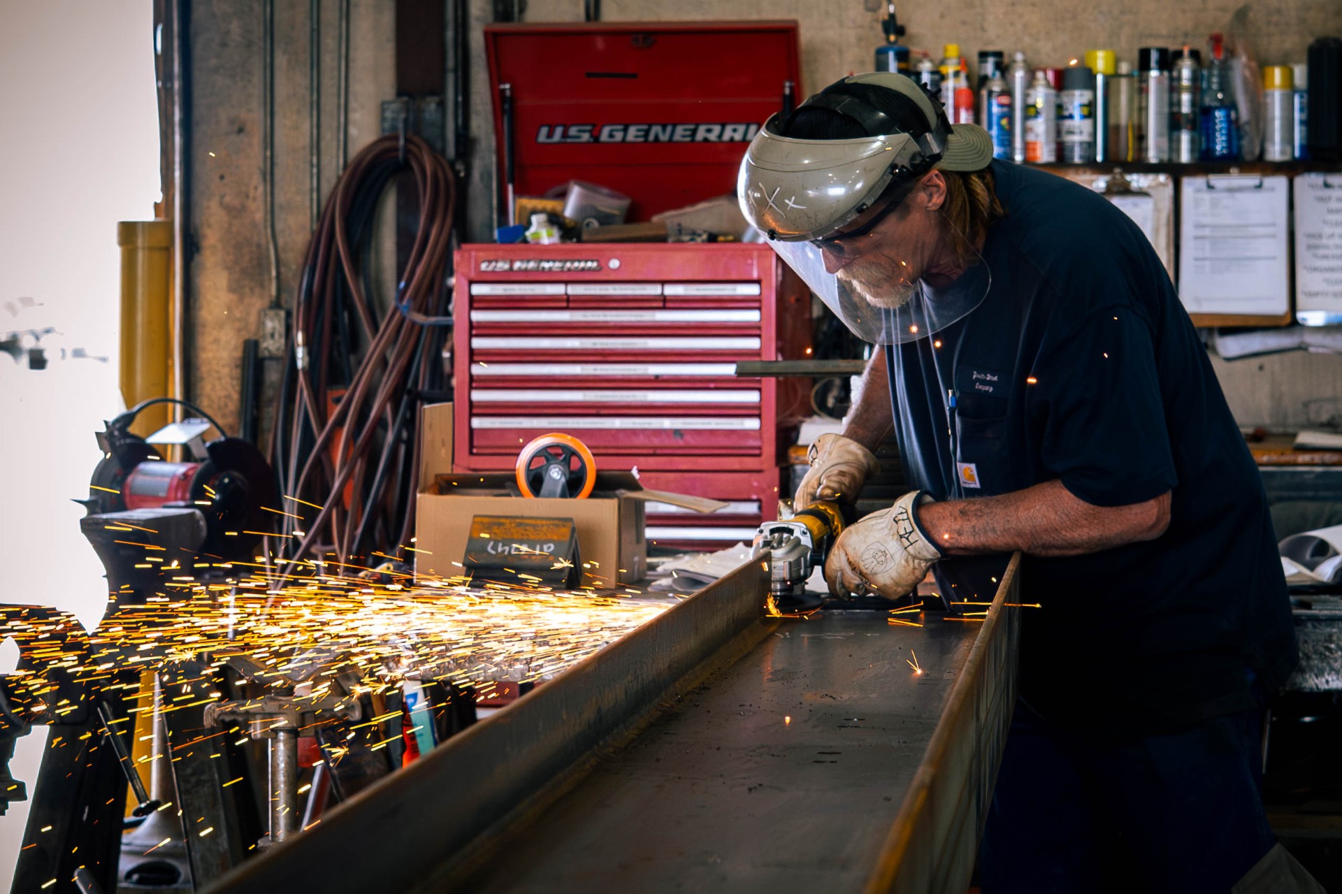Fabricator grinding a structural beam, sparks flying